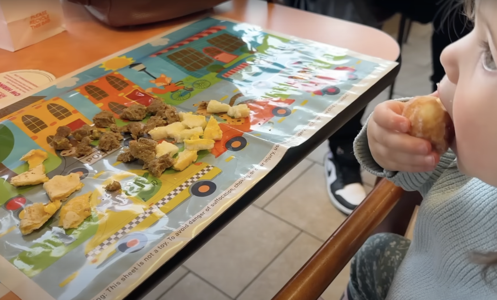 Kid eating on disposable placemat at restaurant.